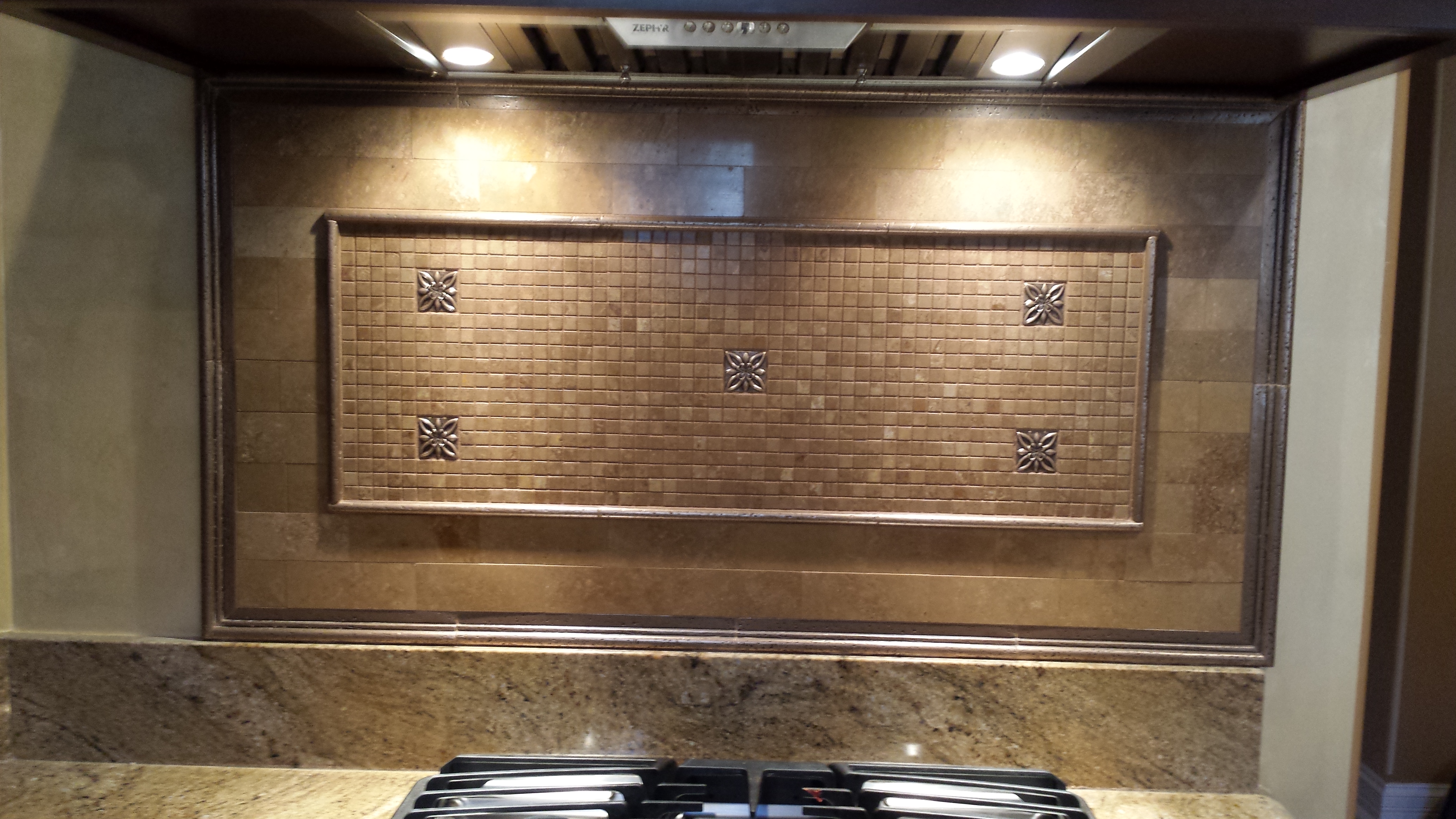 Decorative kitchen backsplash by JackStone in Burr Ridge, Illinois, with a framed mosaic and patterned accents